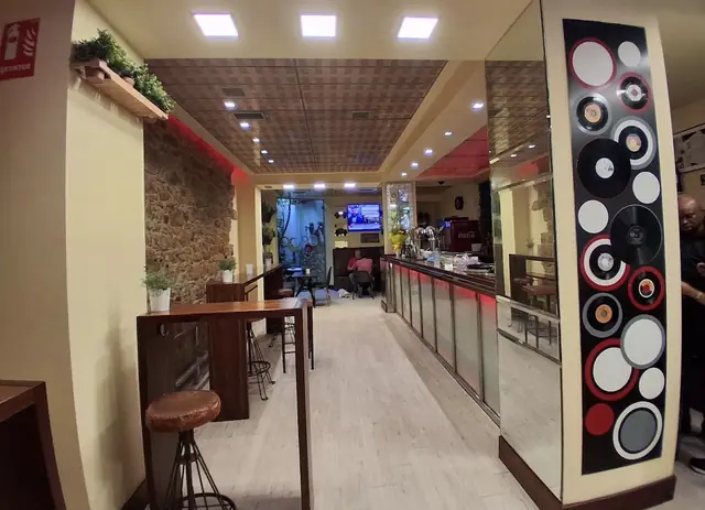 Pasillo del local con una columna decorada con discos de vinilo y la barra al fondo