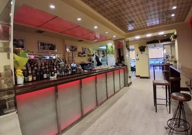 Barra del local con iluminación roja y botellas al fondo