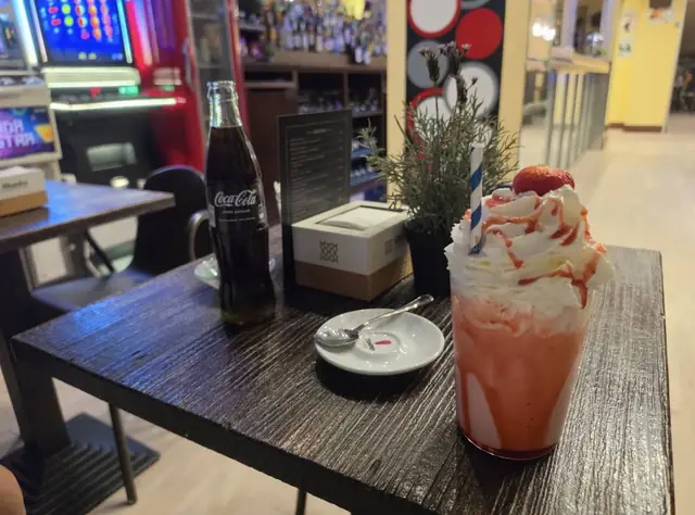 Batido de fresa con nata y sirope sobre una mesa oscura