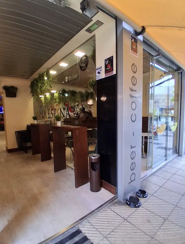 Entrada del local con el cartel «beer · coffee» y un café con espuma en primer plano