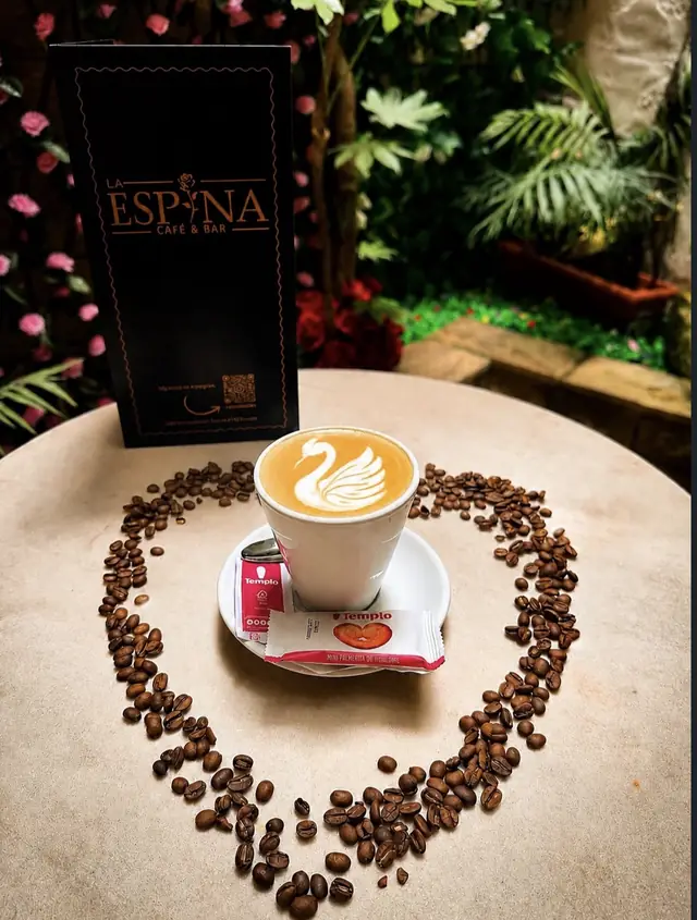 Café con leche con un cisne dibujado en la espuma, rodeado de granos de café en forma de corazón